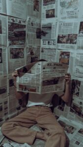 A person sits in a paper-covered corner reading a newspaper, creating a unique setting.